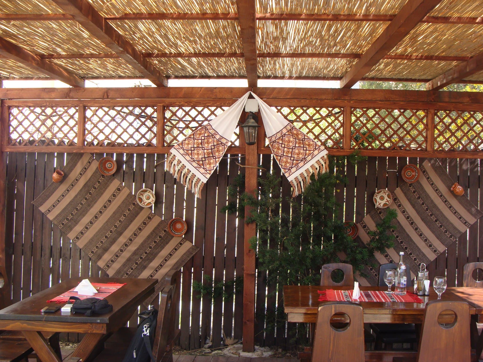 Terasa exterioară a restaurantului, cu mese din lemn și decor rustic